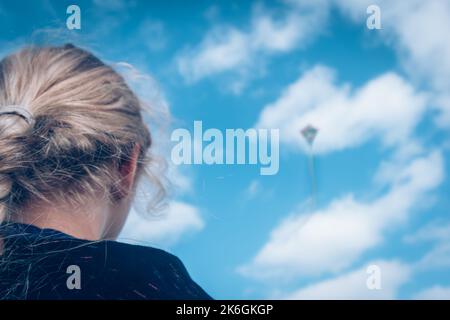 primo piano delle ragazze vista posteriore testa gestire un aquilone nel cielo Foto Stock