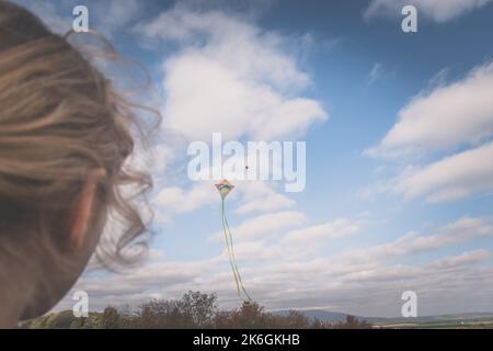 primo piano delle ragazze vista posteriore testa gestire un aquilone nel cielo Foto Stock