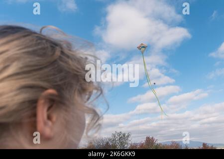 primo piano delle ragazze vista posteriore testa gestire un aquilone nel cielo Foto Stock