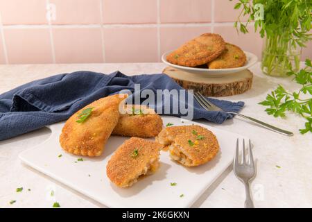 Polpettine di carne e foglie di prezzemolo su piatti di ceramica bianca in una cucina da banco. Foto Stock