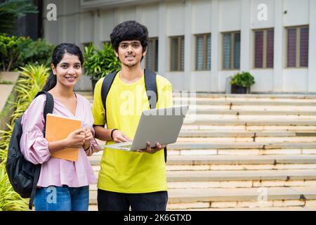 Primo piano di studenti sorridenti felici con uno zaino che tiene il laptop e smilling al camea del campus universitario - concetto di tecnologia, apprendimento e. Foto Stock