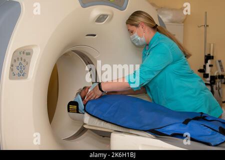 Un medico in un abito medico prepara un paziente per la risonanza magnetica imaging MRI tomografia computerizzata in un ospedale. Foto Stock