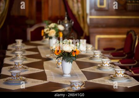 Sul tavolo c'è un vaso con fiori e un vecchio arnese per il tè. Foto Stock