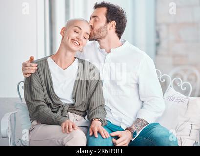 Affettuosa giovane coppia caucasica abbracciante mentre si rilassa insieme a casa. Ragazzo felice abbracciare e baciare la ragazza sulla testa mentre Foto Stock