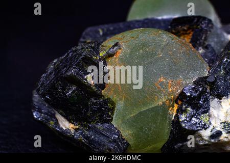 Frammenti di vere sfere di prehnite verde e punte di epidermide verde scuro quasi nero sulla matrice macro isolata su superficie nera Foto Stock
