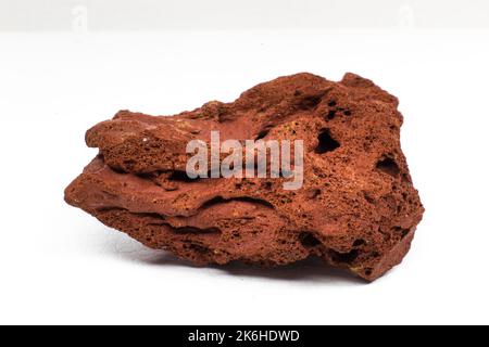 Rosso ruvido pietra lavica macro focalizzata e isolata su superficie bianca macro isolata Foto Stock