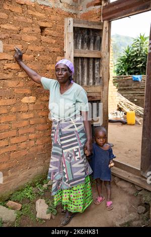 Sylvia Katehero (60) partecipa al progetto reale della LWR (economie rurali e mezzi di sussistenza agricoli) in Kasese, Uganda. Qui, lei si trova con suo nipote, Edwin (2), fuori casa. Sylvia e suo marito vivono con cinque nipoti, tutti di età compresa tra i due e i cinque anni. Prima dell'inizio del progetto, non era in grado di prendersi cura adeguatamente dei nipoti e molti di loro erano malnutriti e spesso si ammalavano. Ci sono stati momenti in cui i bambini erano così malati che temeva per la loro vita. Perché vive così lontano da una struttura sanitaria, e quelli pubblici nelle vicinanze non sono pubblicità Foto Stock