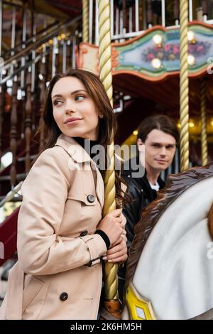 bella giovane donna in trench cappotto cavallo carosello vicino blouded boyfriend, immagine stock Foto Stock