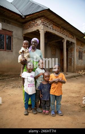 Una donna anziana si trova con i suoi cinque nipoti fuori dalla loro casa di mattoni nel distretto di Kasese, Uganda, Africa orientale. Foto Stock