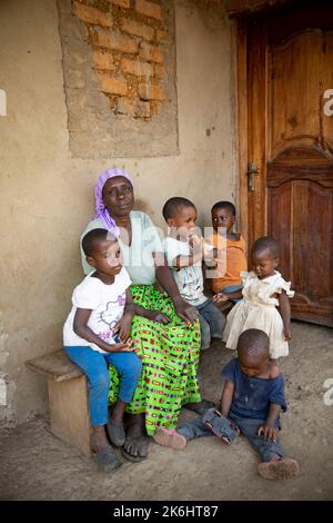 Sylvia Katehero (60) partecipa al progetto reale della LWR (economie rurali e mezzi di sussistenza agricoli) in Kasese, Uganda. Qui, siede con i suoi nipoti fuori della loro casa di nuova costruzione: Eve (2, in bianco), Jordan (3, in pantaloni blu), Godwin (5, In azzurro), Edwin (2, in blu scuro) e Trevor (4, in arancione). Sylvia e suo marito vivono con cinque nipoti, tutti di età compresa tra i due e i cinque anni. Prima dell'inizio del progetto, non era in grado di prendersi cura adeguatamente dei nipoti e molti di loro erano malnutriti e spesso si ammalavano. Ci sono state volte che il chil Foto Stock