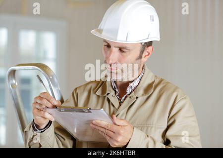 ritratto di un costruttore maschile che scrive sulla clipboard Foto Stock