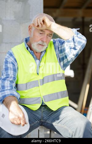 un costruttore anziano stanco sta prendendo una pausa Foto Stock