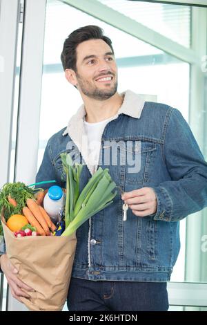 giovane uomo che tornava a casa dopo aver fatto acquisti di generi alimentari Foto Stock
