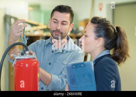 professionista maschio che controlla le condizioni di un estintore Foto Stock