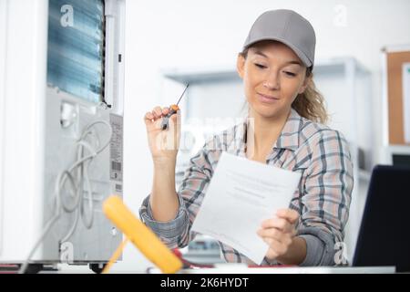 giovane donna sorridente che pulisce l'aria condizionata Foto Stock