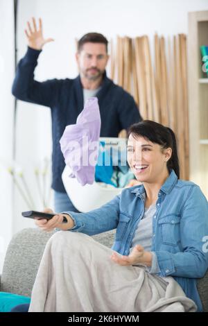 l'uomo infastidito mentre la moglie guarda la tv Foto Stock