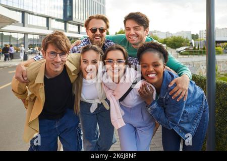 Ritratto di felici e spensierati giovani amici multirazziali in posa insieme sullo sfondo della strada cittadina Foto Stock