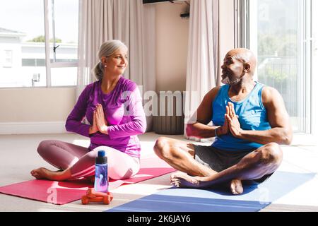 Felice coppia anziana diversa pratica yoga e parlare Foto Stock