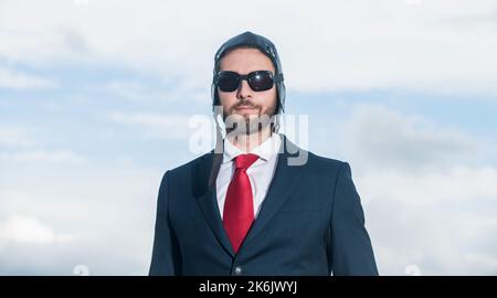 ritratto di uomo d'affari in tuta e cappello pilota su sfondo cielo Foto Stock