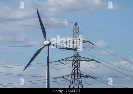 Turbina eolica e pilone elettrico su sfondo cielo blu Foto Stock
