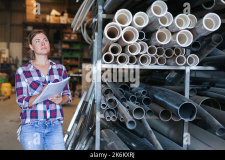 Donna in piedi in magazzino e che tiene i documenti in mano Foto Stock