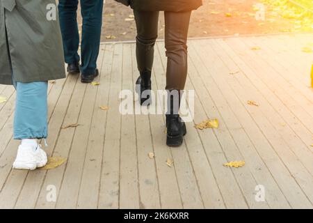 Le gambe delle donne in pantaloni e stivali in pelle camminano tra la folla di passanti Foto Stock