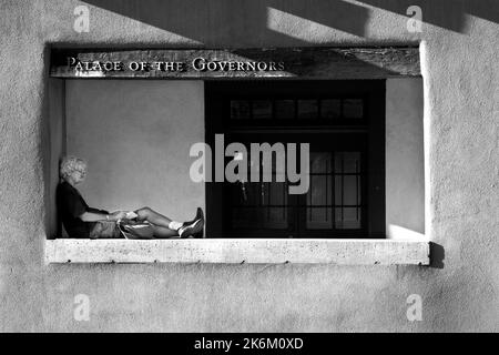 Un uomo scrive nel suo diario mentre si rilassa di fronte allo storico Palazzo dei Governatori a Santa Fe, New Mexico. Foto Stock