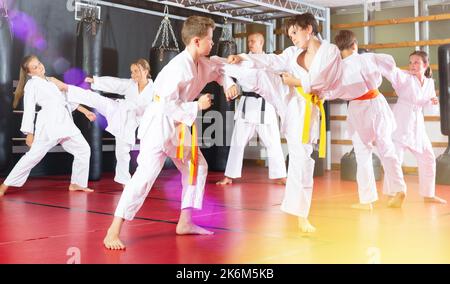 Ragazzi che lavorano in coppia, padroneggiare i calci in classe karate Foto Stock