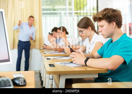 Studenti adolescenti che usano telefoni cellulari durante la lezione Foto Stock