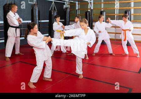 Ragazzi che lavorano in coppia, padroneggiare i calci in classe karate Foto Stock