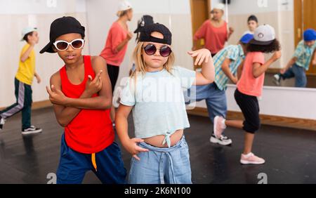 Tween ragazza bionda e ragazzo africano ballare hip-hop in lezione di gruppo Foto Stock