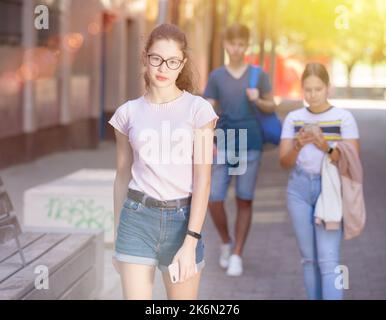 Giovane ragazza sorridente in occhiali che camminano per la città Foto Stock