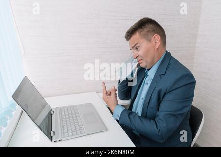 l'uomo toglie la maschera protettiva su sfondo bianco. La fine della pandemia di coronavirus. La quarantena è finita. affaticamento dovuto all'uso di una maschera. Foto Stock