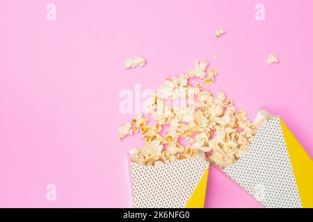 Concetto snack, popcorn dolce galleggiano da due tazze di carta su sfondo rosa. Foto Stock