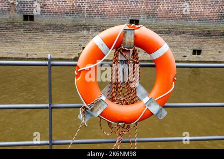 Salvagente arancione su una recinzione ormeggio vicino ad un fiume Foto Stock