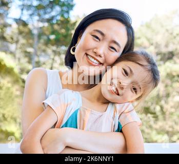 Non posso abbracciarla abbastanza duramente. una adorabile bambina e sua madre abbracciano in giardino. Foto Stock