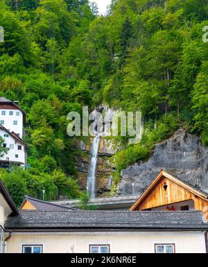 Cascata nella città di Hallstat, Austria. Ruscello di acqua dolce sopra i tetti della città. Foto Stock