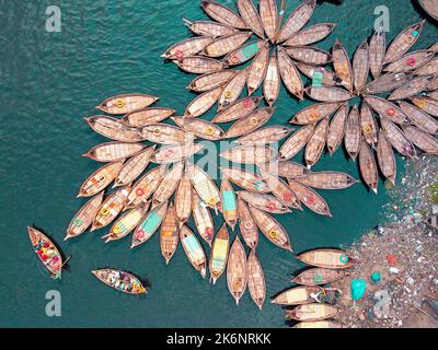 Centinaia di barche di legno si affollano intorno ai loro ormeggi in modelli che assomiglia ai petali di fiore per un'intensa mattina di viaggio sul fiume Buriganga. Foto Stock