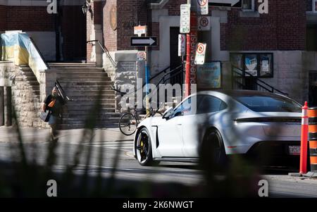 Visto attraverso le piante, una Porsche Taycan Turbo S bianca auto elettrica è parcheggiata in una strada del centro di Toronto in una giornata di sole. Foto Stock