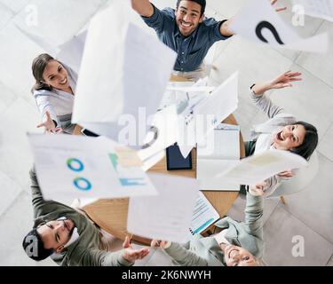 O si esegue il giorno o il giorno si esegue. Scatto aereo di un gruppo vario di uomini d'affari che gettano la documentazione nell'aria in celebrazione mentre nel Foto Stock