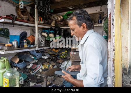 TIKAMGARH, MADHYA PRADESH, INDIA - 14 MAGGIO 2022: Un cobbler indiano che lavora alla riparazione di scarpe nel suo negozio. Foto Stock