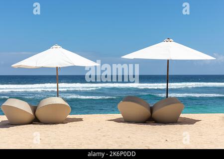 Popolare spiaggia di Melasti (Pantai Melasti), Bukit, Bali, Indonesia. Acqua turchese, scenario oceanico, ombrelloni bianchi con lettini. Foto Stock