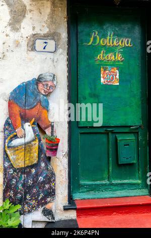 Un dipinto della porta che mostra temi della vita quotidiana della gente del posto, dell'artista Inelda Bassanello, nei pressi del Santuario di Savona. Liguria, Italia. Foto Stock