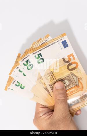 Mano che tiene un gruppo di 50 banconote in euro su sfondo bianco. Spazio di copia Foto Stock