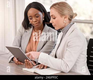 Due menti sono meglio di una. due donne d'affari che pianificano insieme utilizzando un tablet digitale. Foto Stock