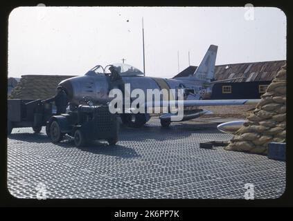 Vista frontale di tre quarti a sinistra di un jet Sabre F-86e nordamericano 'Mach One Mac' (s/n 50-597; 170-19) a terra. Il soprannome "MachOne Mac" è dipinto sul naso. Un tecnico sta guardando all'interno del cockpit. Vista frontale di tre quarti a sinistra di un jet Sabre F-86e nordamericano 'Mach One Mac' (s/n 50-597; 170-19) a terra. Il soprannome "MachOne Mac" è dipinto sul naso. Un tecnico sta guardando all'interno del cockpit. Foto Stock