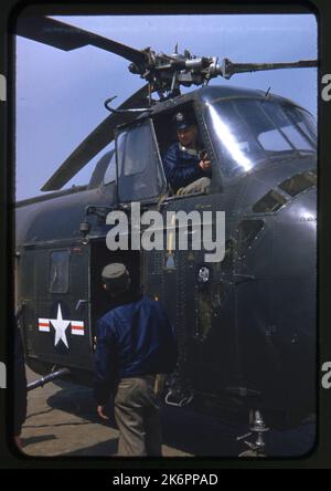 Vista anteriore destra di tre quarti di un Chickasaw Sikorsky H-19 a terra. Sono raffigurati anche due equipe aeree, una accanto all'elicottero, l'altra all'interno seduta sul sedile del pilota. Vista anteriore destra di tre quarti di un Chickasaw Sikorsky H-19 a terra. Sono raffigurati anche due equipe aeree, una accanto all'elicottero, l'altra all'interno seduta sul sedile del pilota. Foto Stock