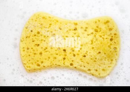 Primo piano di spugna blu e straccio in lavello da cucina pieno di schiuma Foto Stock