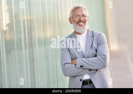 Sicuro uomo d'affari anziano felice che indossa il vestito in piedi all'aperto, ritratto. Foto Stock