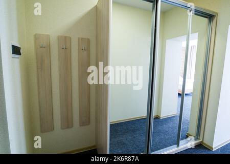 Ingresso lungo e luminoso con porte in un nuovo hotel con armadio Foto Stock